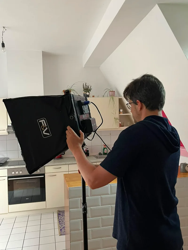 Michael Tartsch richtet von hinten gesehen eine Leuchte mit Softbox aus, dahinter die Küche